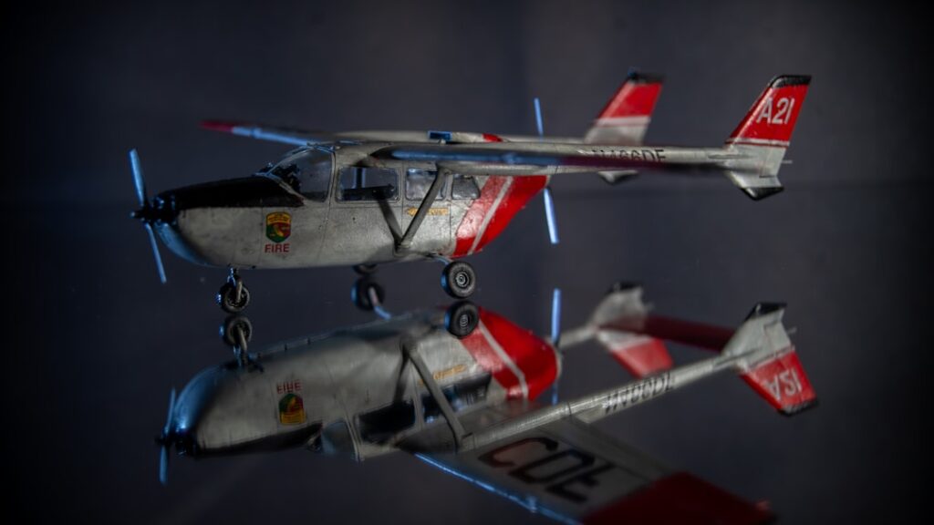 A small white and red airplane with its reflection.